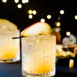 A Holiday Cocktail with a pear for decoration on a dark tablescape