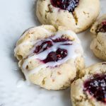 Close up of 3 thumbprint cookies one plain, one topped with sugar and the last drizzled with icing.