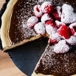 A close up of a chocolate and raspberry cheesecake with a piece missing