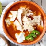 Overhead shot of a bowl of chicken tortilla soup topped with sour cream and jalapenos