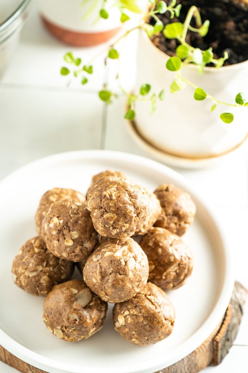 Easy bliss balls stacked on a plate with a plant nearby.