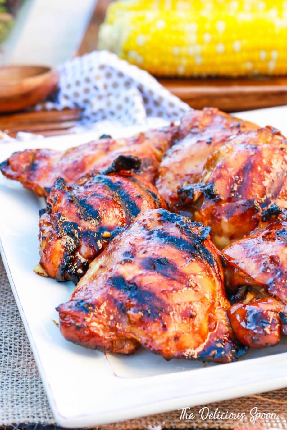 Honey Grilled Chicken Thighs on a wood plate with some corn on the cob