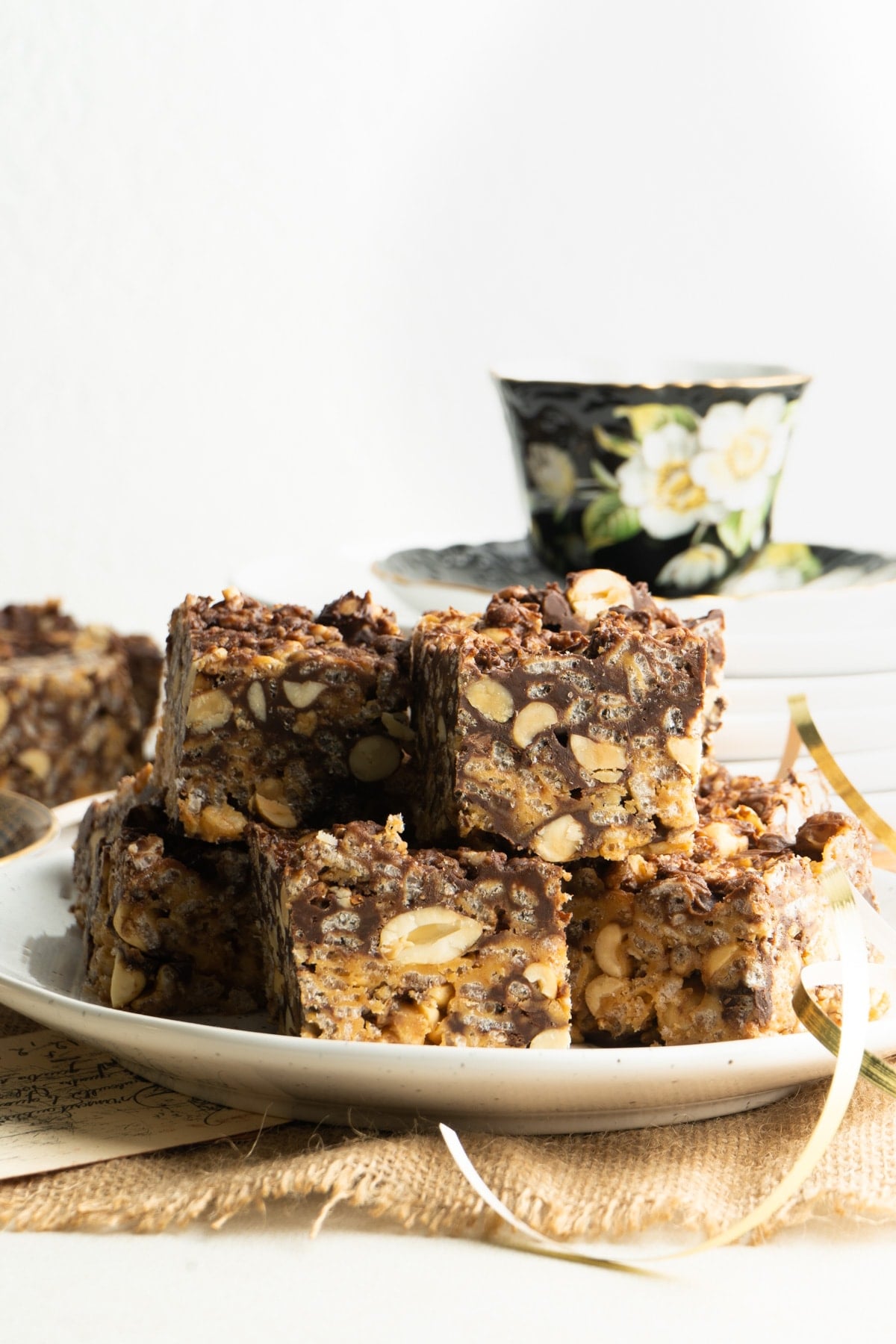 chocolate peanut butter rice krispie treats on a plate with a tea cup in background.