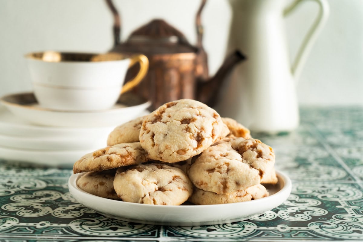 A plate of Skor cookies on a table with a teapot.