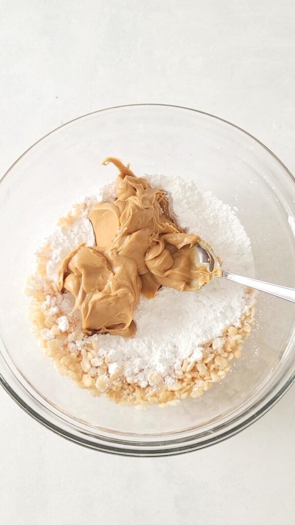 Rice Krispies, peanut butter and icing sugar in a bowl to make buckeye balls with rice krispies.