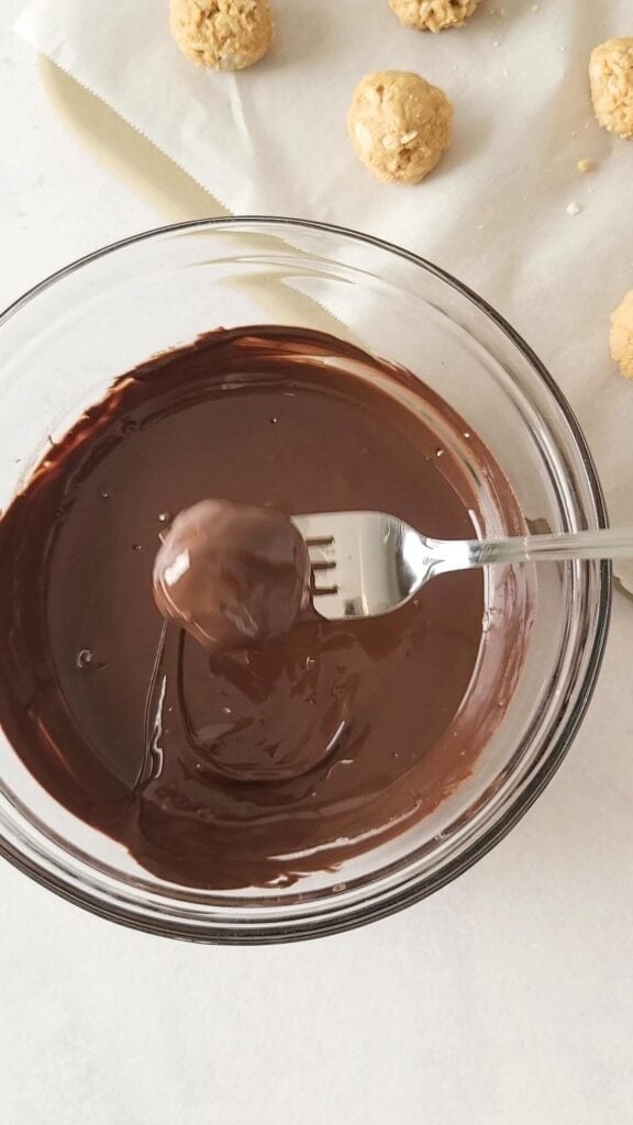 A peanut butter ball recipe being dipped in chocolate with a fork