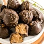 A pyramid of old fashioned peanut butter balls on a white plate.