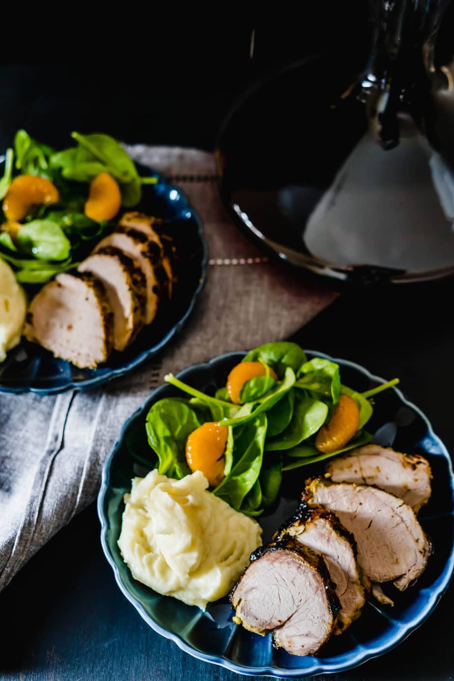 A cuban pork recipe using pork loin sliced on two plates with potatoes and salad.