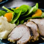 Close up of a mojo pork tenderloin recipe with salad and potatoes
