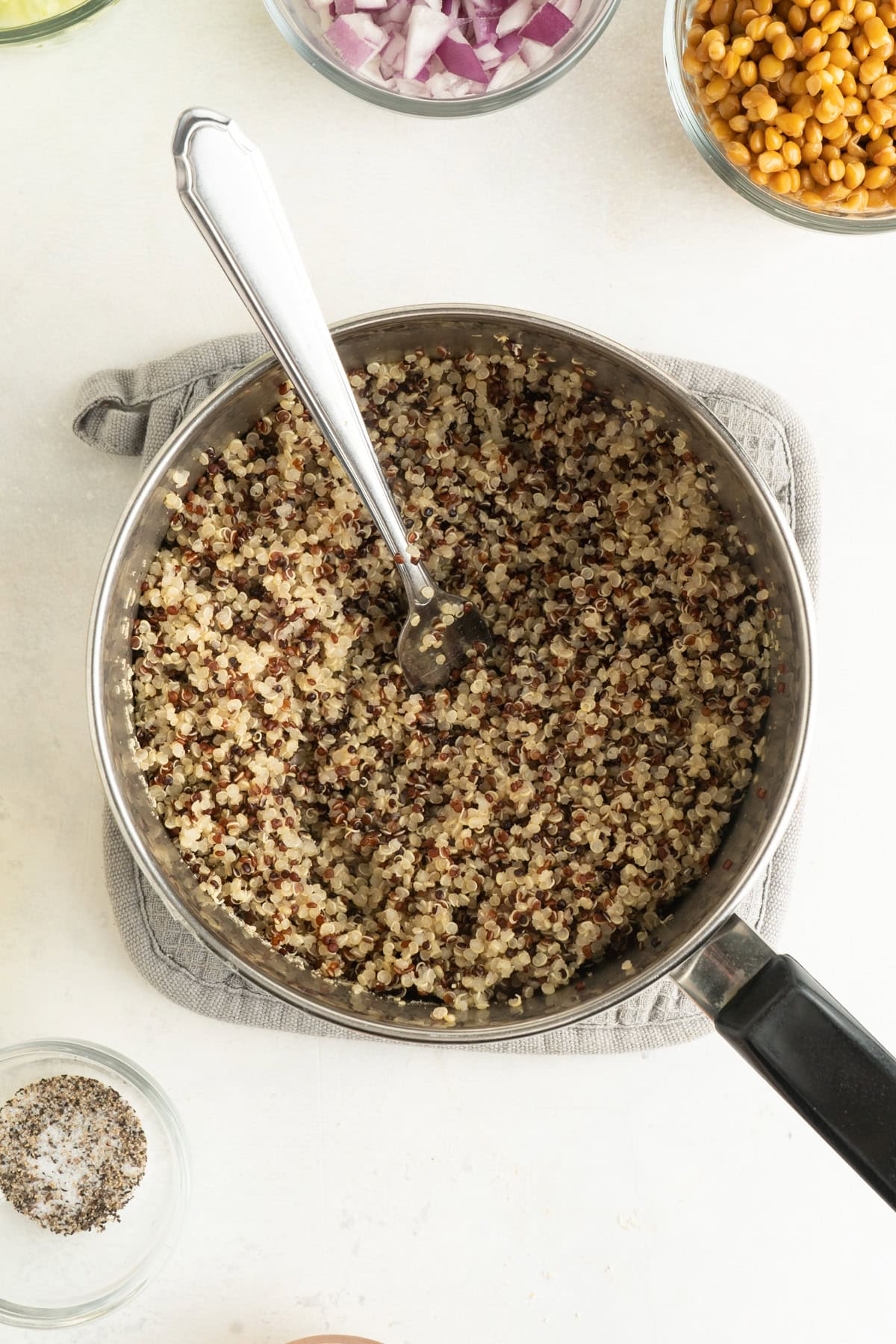 A pot of cooked quinoa being fluffed with a fork.