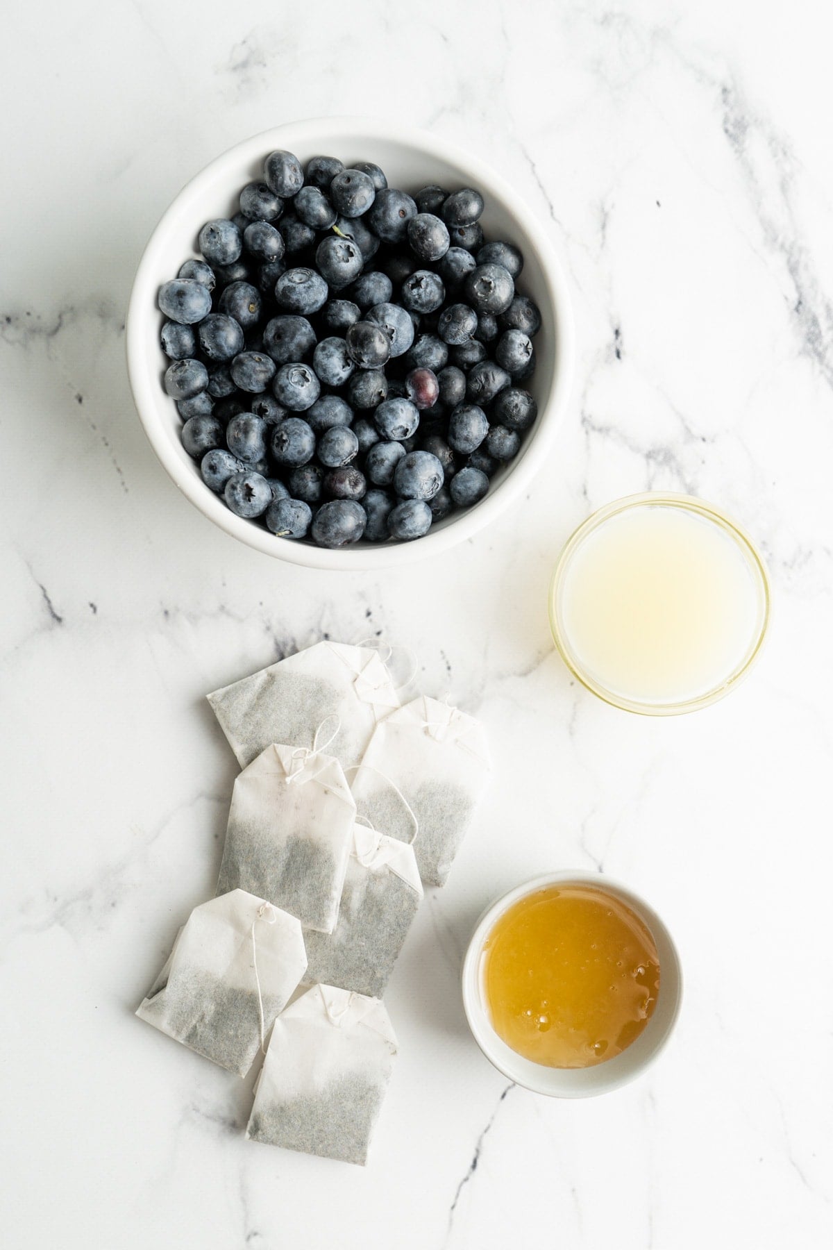 Ingredients for a sweet green tea made with blueberries, green tea, honey and lemon juice.