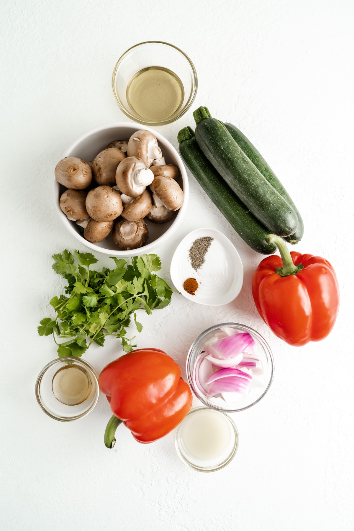 Ingredients for cilantro lime air fryer roasted vegetables - peppers, zucchini, red onion, mushrooms vinaigrette with lime, cilantro and chili powder.