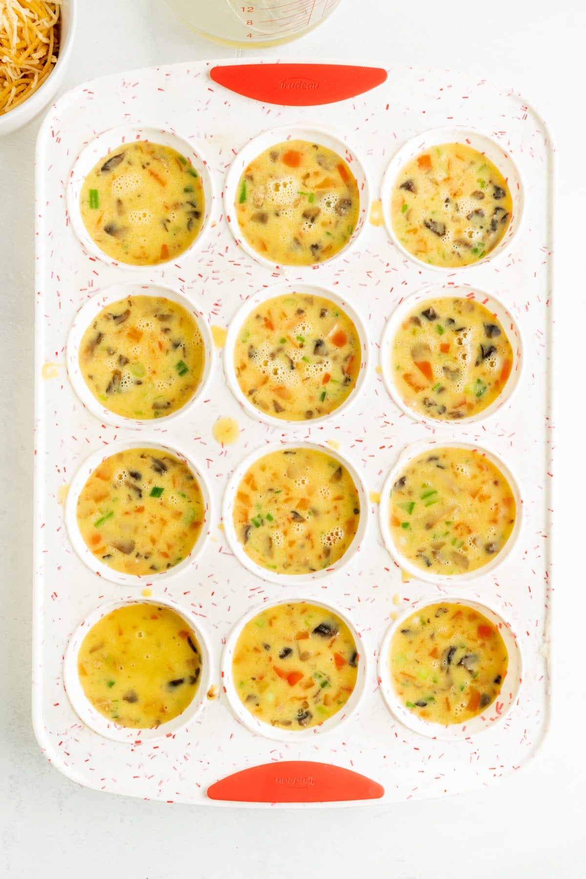 Denver Omelet muffins in a muffin tin unbaked.