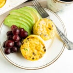Two Omelette Muffins on a plate with a fork and fruit.