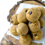 An overhead shot of a pile of chocolate chip energy bites on a rustic wood board with the bark on