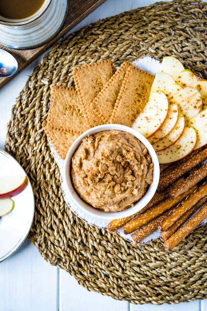 Overhead shot of some dessert hummus on a plate with cookies, pretzels and apple slices