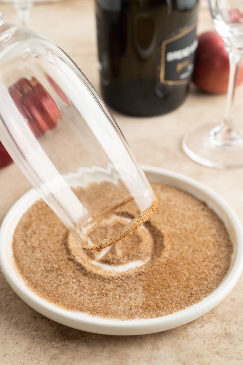 A champagne flute being rimmed with cinnamon sugar.