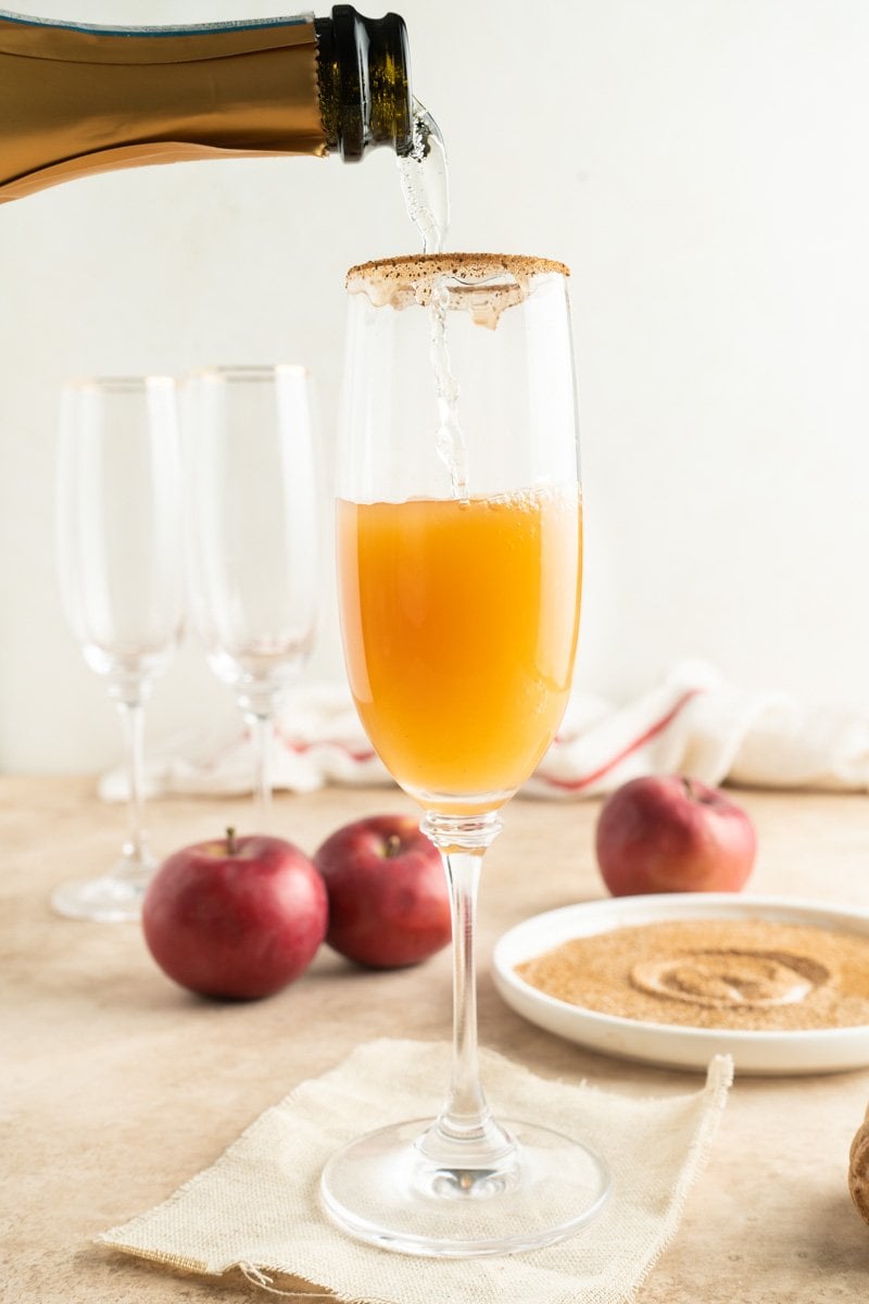 A flute with champagne being poured into it.