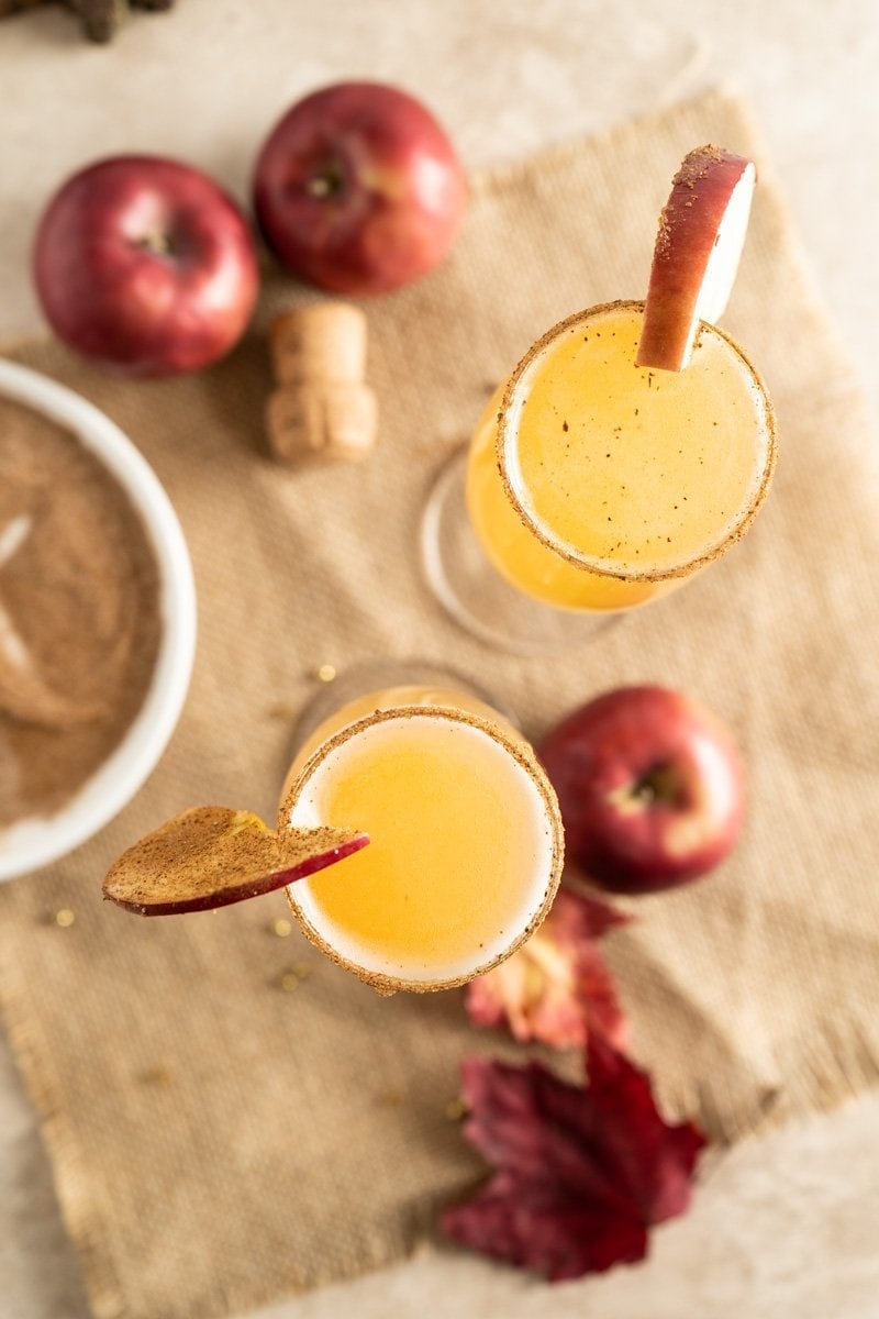 Two thanksgiving mimosas on a table with apples.
