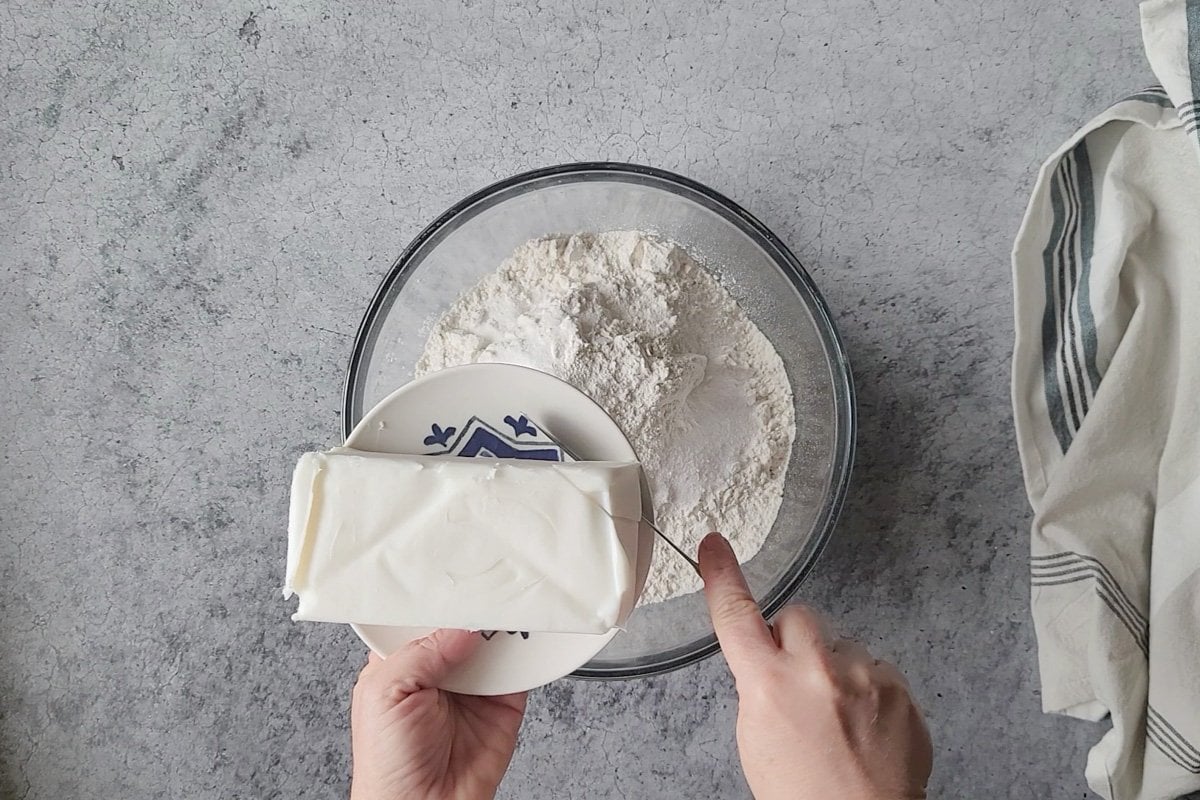 A bowl of flour with lard being cut into it.