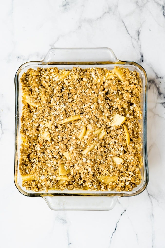 Overhad shot of a prepared apple crisp before being baked on a white backgournd