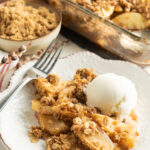 A bowl of apple crisp and ice cream on a wood table