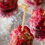 A close up of a turkey meatball appetizer in cranberry sauce on a silver platter