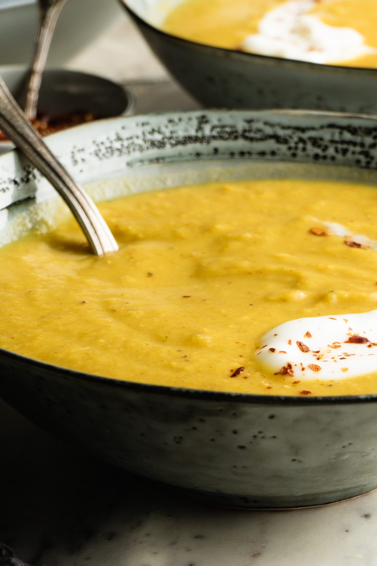 A bowl of spicy red lentil soup with a spoon.