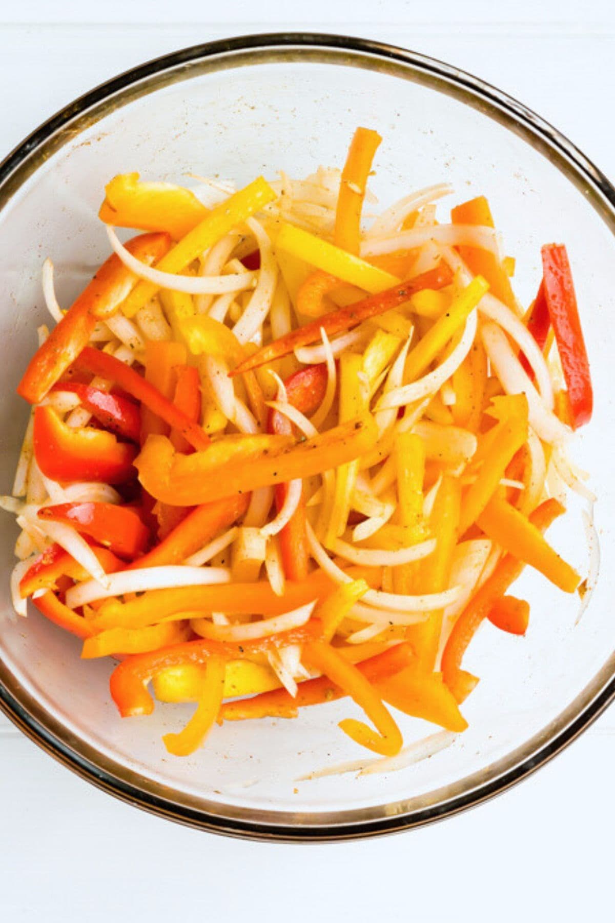 Sliced peppers and onions in a bowl.