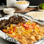 Shrimp and steak fajitas on a sheet pan.