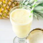 A smoothie with pineapple and coconut on a white table