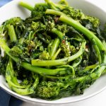 Bowl of Sauteed Broccoli Rabe in a white bowl with a blue napkin