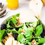 A bowl of winter salad with bosc pears, blackberries and walntuts
