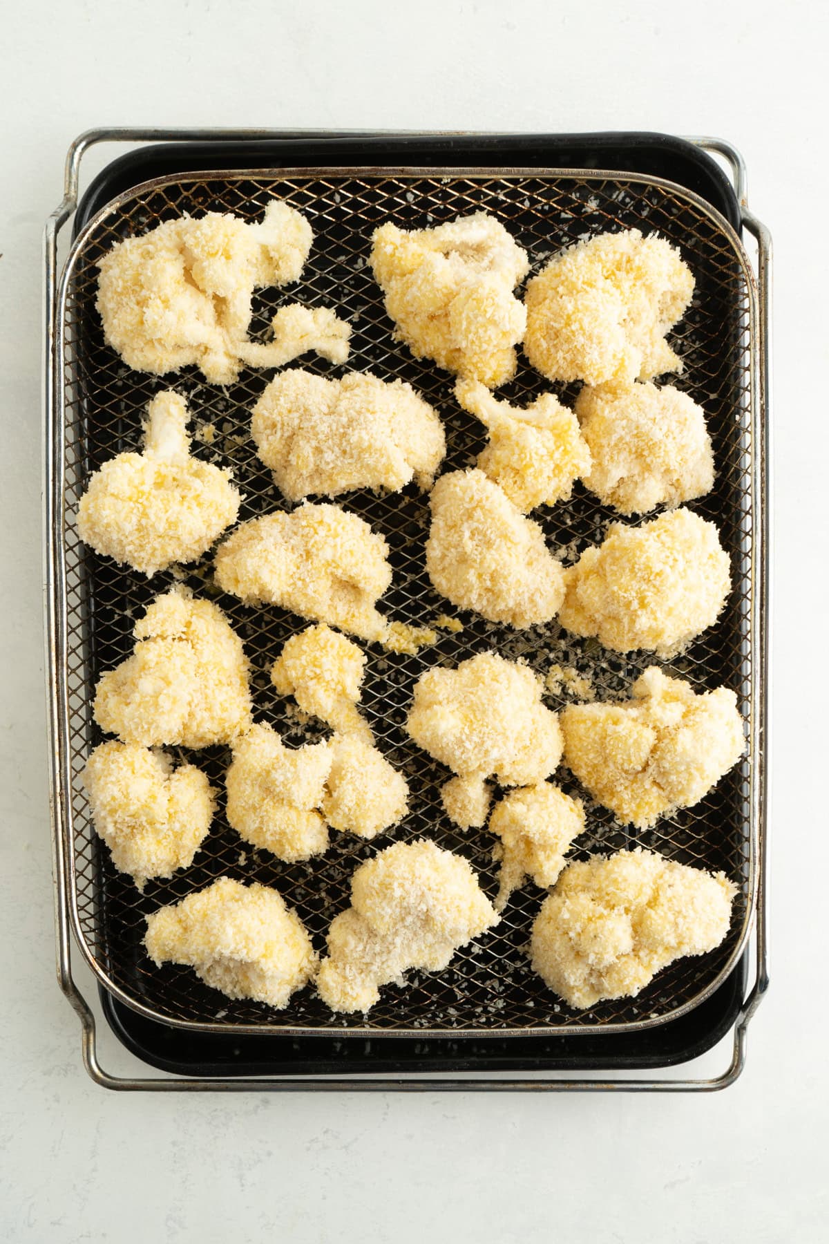 Panko coated cauliflower wings on a wire air fryer tray.