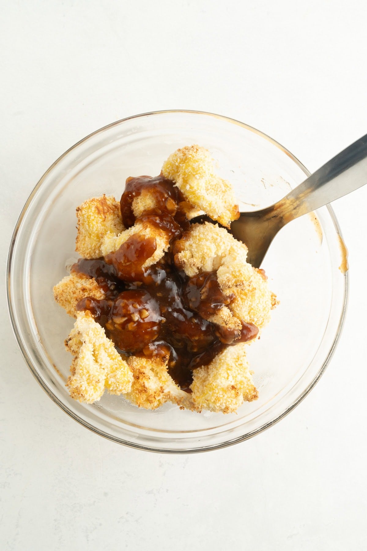 Air fried cauliflower wings being tossed in an Asian BBQ sauce.