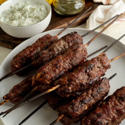 A plate of beef kofta skewers on a table.