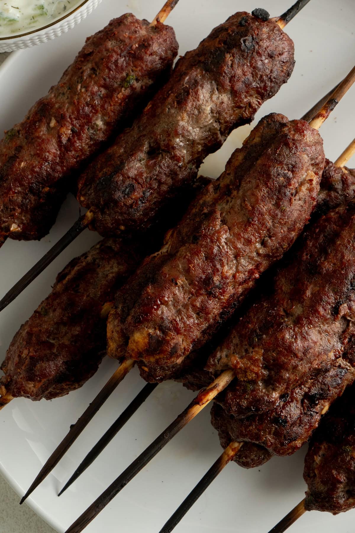 Close up of some kafta kebabs on a white plate.