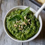 Fresh basil walnut pesto in a white bowl with a spoon