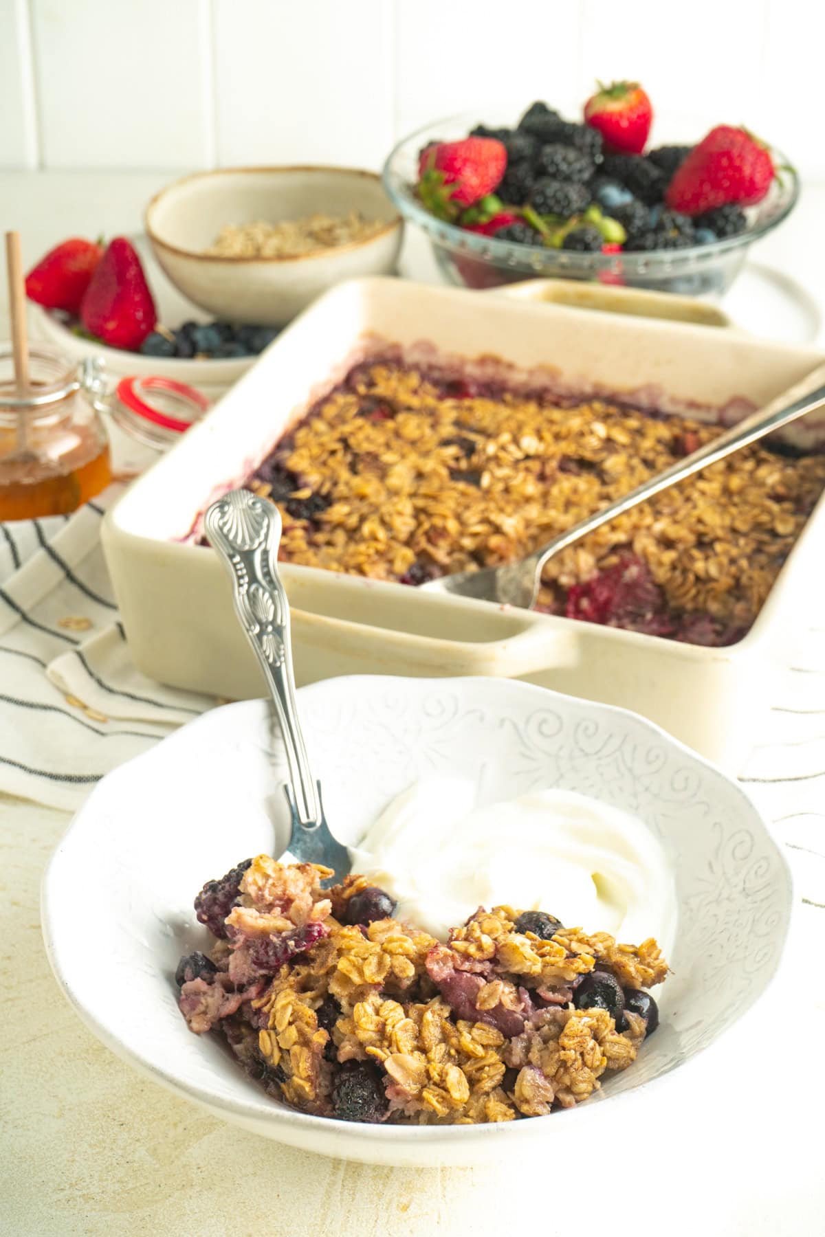 Baked fruit oatmeal in a bowl with yogurt on a table.