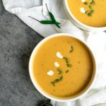 Bowls of Thai pumpkin soup on a table with a white napkin and Thai green chilis