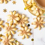 Spritz cookies on a white table with a gold tea cup