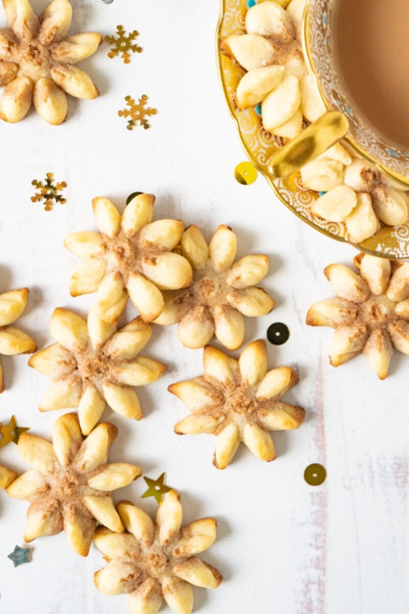 A table filled with pressed butter cookies and a cup of tea.