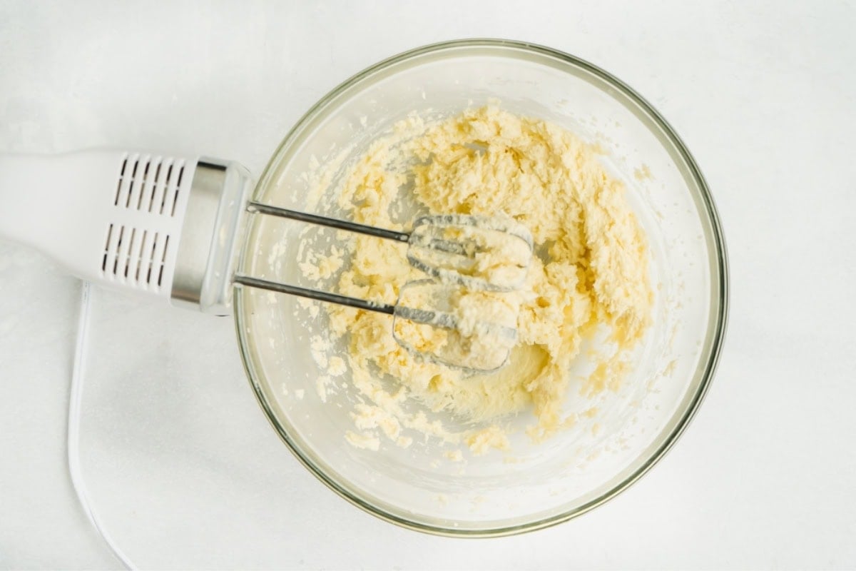 Butter and sugar being whipped in a bowl until fluffy.