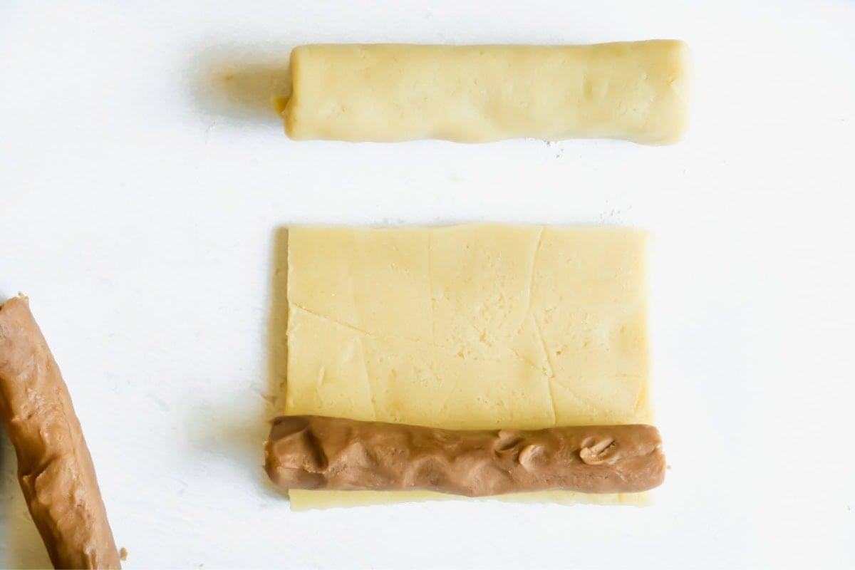 A log of chocolate dough being wrapped in a rectangle of vanilla dough.