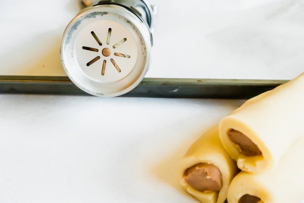 A cookie press with dough inside showing the flower stamp.