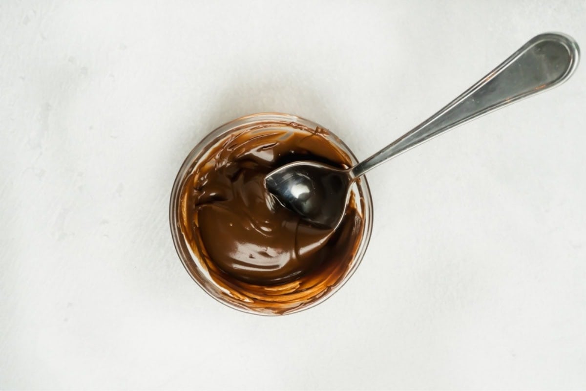 Melted chocolate in a small bowl with a spoon.