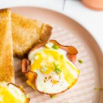 A baked egg cup topped with green onions with a side of toast