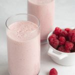 Two glasses from overhead filled with a green tea smoothie made with raspberries