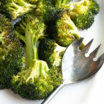 Garlic roasted broccoli on a white platter with a serving fork
