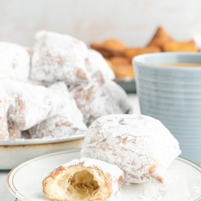 Cafe du Monde style beignets and coffee with one beignet less a bite.